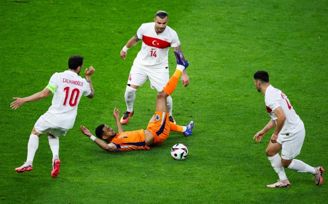 Netherlands' forward #11 Cody Gakpo (C) falls as he fights for the ball with Turkey's midfielder #10 Hakan Calhanoglu and Turkey's defender #14 Abdulkerim Bardakci during the UEFA Euro 2024 quarter-final football match between the Netherlands and Turkey at the Olympiastadion Berlin in Berlin on July 6, 2024. (Photo by Ronny HARTMANN / AFP)