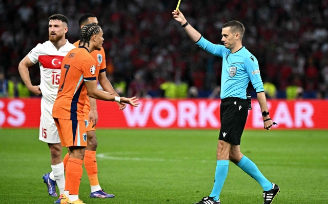 French referee Clement Turpin (R) gives a yellow card to  Netherlands' forward #07 Xavi Simons  during the UEFA Euro 2024 quarter-final football match between the Netherlands and Turkey at the Olympiastadion in Berlin on July 6, 2024. (Photo by JAVIER SORIANO / AFP)
