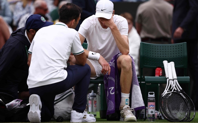 Italy's Jannik Sinner talks to staff during a medical time-out in his match against Russia's Daniil Medvedev during their men's singles quarter-final tennis match on the ninth day of the 2024 Wimbledon Championships at The All England Lawn Tennis and Croquet Club in Wimbledon, southwest London, on July 9, 2024. (Photo by HENRY NICHOLLS / AFP) / RESTRICTED TO EDITORIAL USE