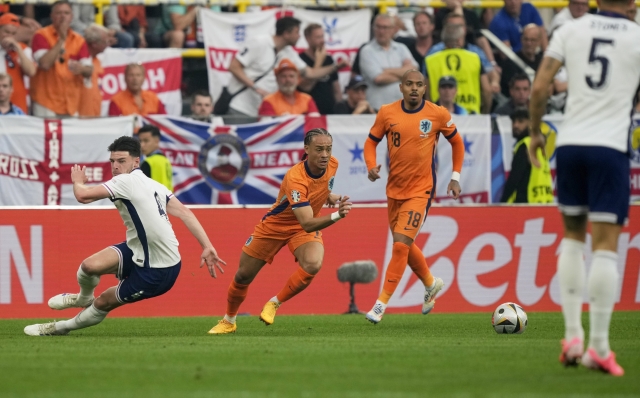 Xavi Simons of the Netherlands, center, steals the ball from England's Declan Rice, left to score the opening goal during a semifinal match between the Netherlands and England at the Euro 2024 soccer tournament in Dortmund, Germany, Wednesday, July 10, 2024. (AP Photo/Martin Meissner)