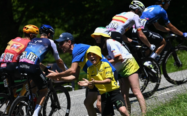 Spectators cheer as the lead breakaway cycles during the 15th stage of the 111th edition of the Tour de France cycling race, 197,7 km between Loudenvielle and Plateau de Beille, in the Pyrenees mountains, southwestern France, on July 14, 2024. (Photo by Marco BERTORELLO / AFP)