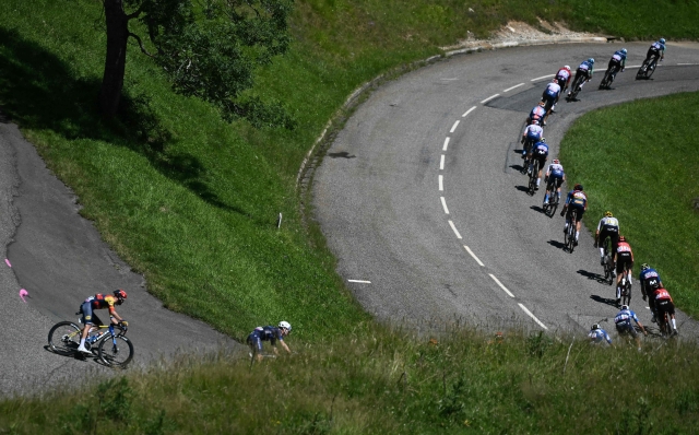 The pack of riders (peloton) cycles during the 15th stage of the 111th edition of the Tour de France cycling race, 197,7 km between Loudenvielle and Plateau de Beille, in the Pyrenees mountains, southwestern France, on July 14, 2024. (Photo by Marco BERTORELLO / AFP)