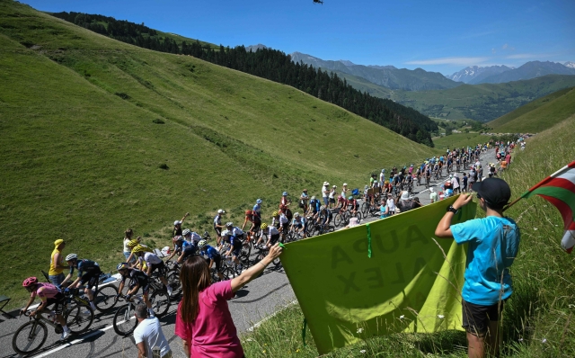 TOPSHOT - The pack of riders (peloton) cycles in the ascent of the Col de Peyresourde during the 15th stage of the 111th edition of the Tour de France cycling race, 197,7 km between Loudenvielle and Plateau de Beille, in the Pyrenees mountains, southwestern France, on July 14, 2024. (Photo by Marco BERTORELLO / AFP)