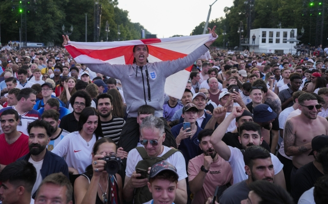 A fan holds the flag of England as he celebrates with others in central Berlin before the start of the final match between Spain and England at the Euro 2024 soccer tournament in Germany, Sunday, July 14, 2024. (AP Photo/Markus Schreiber)