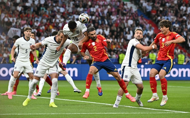 England's midfielder #10 Jude Bellingham (CL) heads the ball against Spain's defender #02 Dani Carvajal (CR) during the UEFA Euro 2024 final football match between Spain and England at the Olympiastadion in Berlin on July 14, 2024. (Photo by JAVIER SORIANO / AFP)