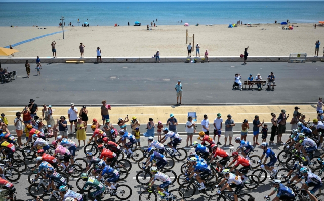 The pack of riders (peloton) cycles along the Mediterranean coast during the 16th stage of the 111th edition of the Tour de France cycling race, 188,6 km between Gruissan and Nimes, southern France, on July 16, 2024. (Photo by Marco BERTORELLO / AFP)