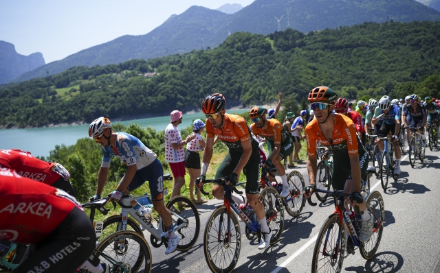 Britain's Simon Yates, right in orange, rides in the pack as they pass Sautet lake during the eighteenth stage of the Tour de France cycling race over 179.5 kilometers (111.5 miles) with start in Gap and finish in Barcelonette, France, Thursday, July 18, 2024. (AP Photo/Daniel Cole)