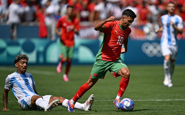 Morocco's forward #10 Ilias Akhomach (R) outflanks Argentina's midfielder #08 Cristian Medina in the men's group B football match between Argentina and Morocco during the Paris 2024 Olympic Games at the Geoffroy-Guichard Stadium in Saint-Etienne on July 24, 2024. (Photo by Arnaud FINISTRE / AFP)