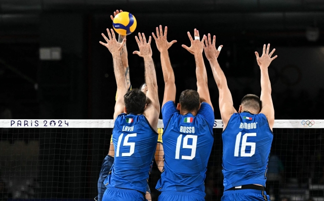 (LtoR) Italy's #15 Daniele Lavia, Italy's #19 Roberto Russo and Italy's #16 Yuri Romano jump to block the ball during the men's preliminary round volleyball match between Italy and Brazil during the Paris 2024 Olympic Games at the South Paris Arena 1 in Paris on July 27, 2024. (Photo by Natalia KOLESNIKOVA / AFP)