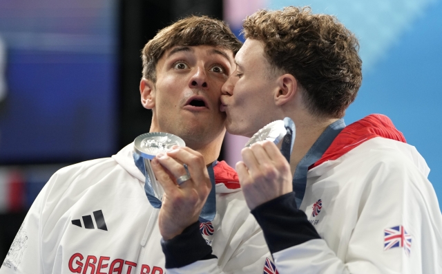 Britain's Thomas Daley and Noah Williams celebrate on the podium after winning the silver medal in the men's synchronised 10m platform diving final at the 2024 Summer Olympics, Monday, July 29, 2024, in Saint-Denis, France. (AP Photo/Lee Jin-man)