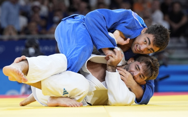 Italy's Manuel Lombardo and Moldova's Adil Osmanov, top, compete during their men -73 kg bronze medal final match in team judo competition at Champ-de-Mars Arena during the 2024 Summer Olympics, Monday, July 29, 2024, in Paris, France. (AP Photo/Eugene Hoshiko)