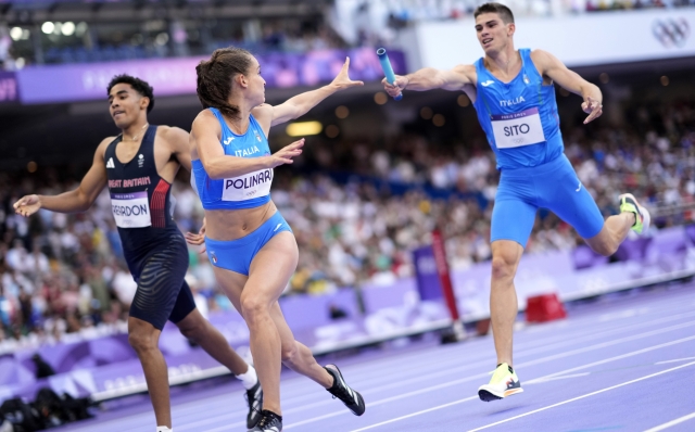 Anna Polinari, left, of Italy, receives the baton from teammate Luca Sito, right, in a 4 x 400 meters relay mixed round 1 heat at the 2024 Summer Olympics, Friday, Aug. 2, 2024, in Saint-Denis, France. (AP Photo/Bernat Armangue)