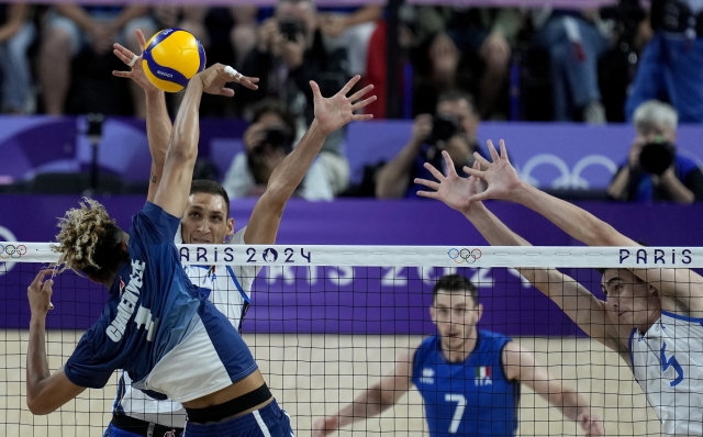 Roberto Russo, back left, of Italy, blocks the ball hit by Barthelemy Chinenyeze (1) of France, during a semifinal men's volleyball match at the 2024 Summer Olympics, Wednesday, Aug. 7, 2024, in Paris, France. (AP Photo/Dolores Ochoa)