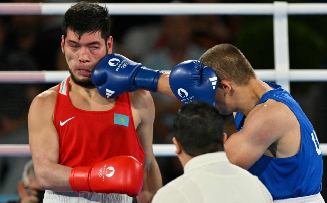 Kazakhstan's Nurbek Oralbay and Ukraine's Oleksandr Khyzhniak (Blue) compete in the men's 80kg final boxing match during the Paris 2024 Olympic Games at the Roland-Garros Stadium, in Paris on August 7, 2024. (Photo by MOHD RASFAN / AFP)