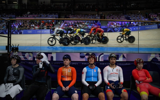 TOPSHOT - Athletes wait for the start of the the women's track cycling keirin as men compete in the keirin during the Paris 2024 Olympic Games at the Saint-Quentin-en-Yvelines National Velodrome in Montigny-le-Bretonneux, south-west of Paris, on August 8, 2024. (Photo by JEFF PACHOUD / AFP)