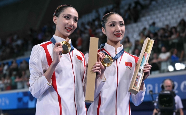 Gold medallists China's Wang Liuyi and Wang Qianyi pose during the podium ceremony of the duet artistic swimming event during the Paris 2024 Olympic Games at the Aquatics Centre in Saint-Denis, north of Paris, on August 10, 2024. (Photo by Oli SCARFF / AFP)