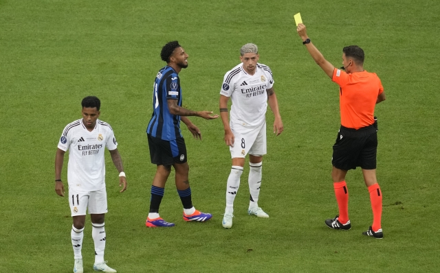 Referee Sandro Scharer, right, shows a yellow card to Atalanta's Ederson, second left, during the UEFA Super Cup Final soccer match between Real Madrid and Atalanta at the Narodowy stadium in Warsaw, Poland, Wednesday, Aug. 14, 2024. (AP Photo/Darko Vojinovic)