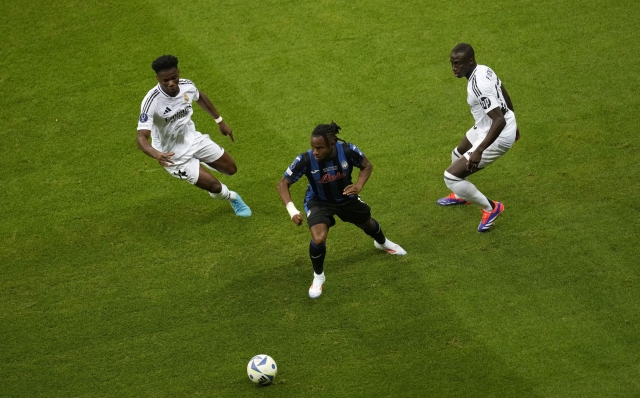 Atalanta's Ademola Lookman, center, goes for the ball between Real Madrid's Ferland Mendy, right, and Real Madrid's Aurelien Tchouameni during the UEFA Super Cup Final soccer match between Real Madrid and Atalanta at the Narodowy stadium in Warsaw, Poland, Wednesday, Aug. 14, 2024. (AP Photo/Darko Vojinovic)