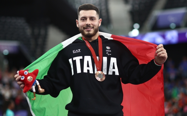 PARIS, FRANCE - SEPTEMBER 06: Donato Telesca of Team Italy celebrates with the national flag on the podium following the Men's up to 72KG Final on day nine of the Paris 2024 Summer Paralympic Games at Porte de La Chapelle Arena on September 06, 2024 in Paris, France. (Photo by Naomi Baker/Getty Images)