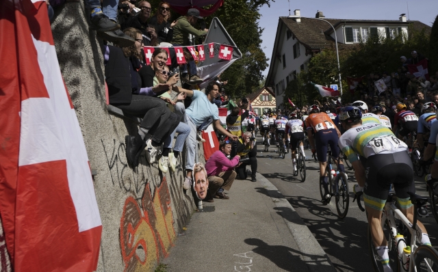 Fans cheer the The peloton climbing Zuricherstrasse during the Men Elite road race of the Cycling and Para-cycling Road World Championships in Zurich, Switzerland, Sunday, Sept. 29, 2024. (Simon Wilkinson/SWpix.com/Pool Photo via AP)