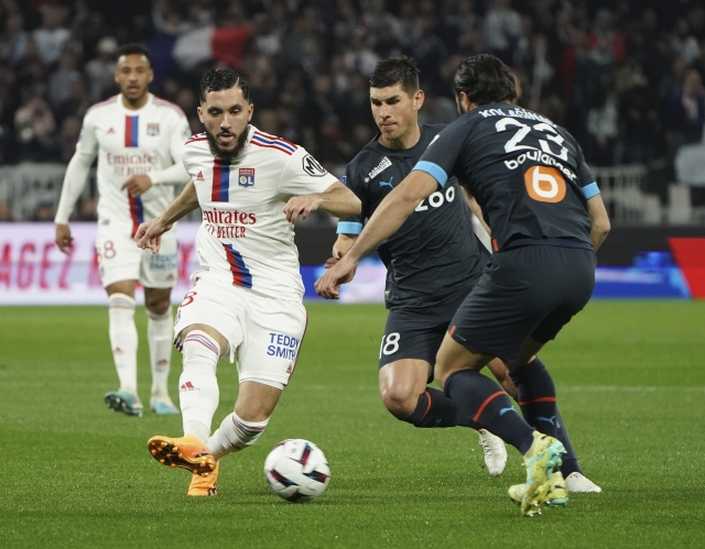 Lyon's Rayan Cherki kicks the ball ahead of Marseille's Sead Kolasinac, right, during the French League One soccer match between Lyon and Marseille at the Groupama stadium, in Decines, near Lyon, France, Sunday, April 23, 2023. (AP Photo/Laurent Cipriani)