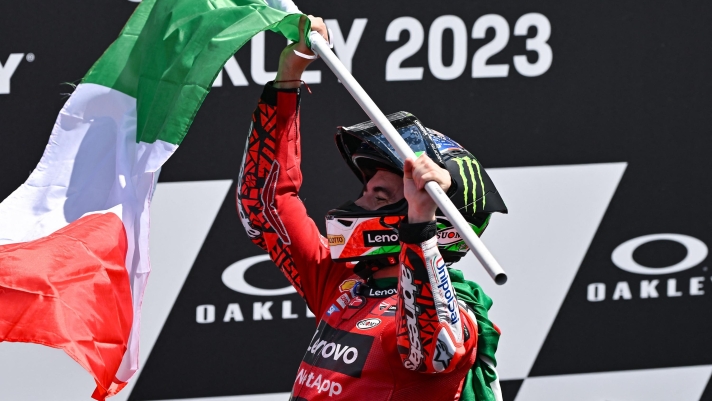 Ducati Italian rider Francesco Bagnaia waves the Italian flag as he celebrates after winning the Italian MotoGP race at Mugello Circuit in Mugello, on June 11, 2023. (Photo by Filippo MONTEFORTE / AFP)
