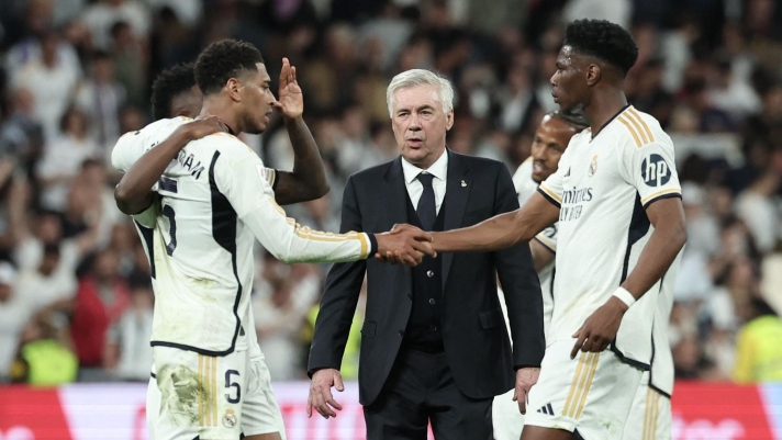 TOPSHOT - Real Madrid's Italian coach Carlo Ancelotti (C) and Real Madrid's players celebrate their victory at the end of the Spanish league football match between Real Madrid CF and FC Barcelona at the Santiago Bernabeu stadium in Madrid on April 21, 2024. (Photo by Thomas COEX / AFP)