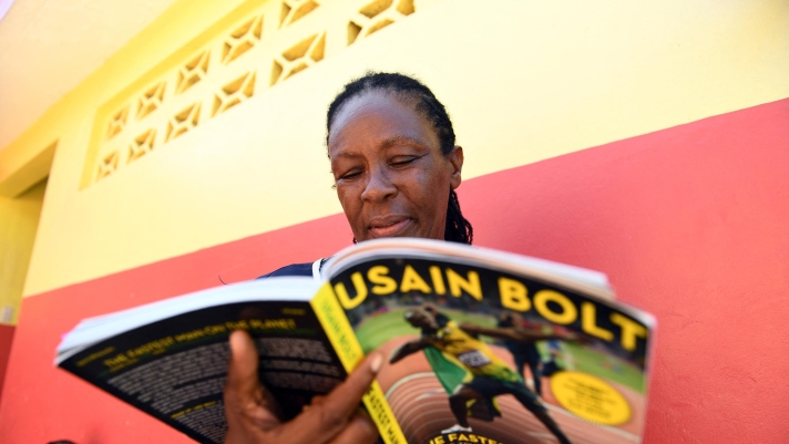 Jamaican sprinter Usain Bolt's elementary teacher Sheron Seivwright reads a book about him during a break at the Waldensia elementary school in Sherwood Content on June 7, 2017. Usain Bolt, the greatest sprinter in history with eight Olympic golds, 11 world titles and three world records, will retire from international competition after the IAAF world championships in August. (Photo by Jewel SAMAD / AFP)