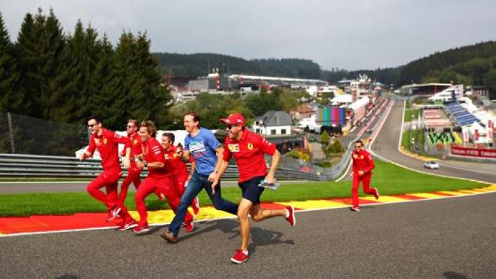 Vettel e parte dello staff Ferrari di corsa all'Eau Rouge di Spa. Getty