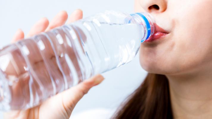 una donna beve dell'acqua da una bottiglia di plastica