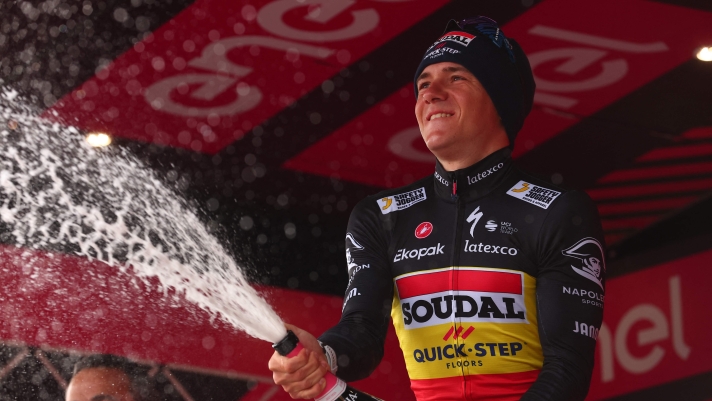 Soudal - Quick Step's Belgian rider Remco Evenepoel sprays sparkling wine as he celebrates on the podium after winning the ninth stage of the Giro d'Italia 2023 cycling race, a 35 km individual time trial between Savignano sul Rubicone and Cesena, on May 14, 2023. (Photo by Luca Bettini / AFP)