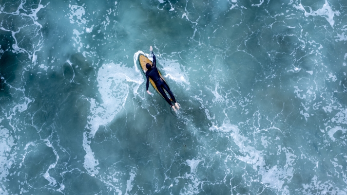An overhead drone shot of a surfer in the wavy sea, Newport Beach, California, USA