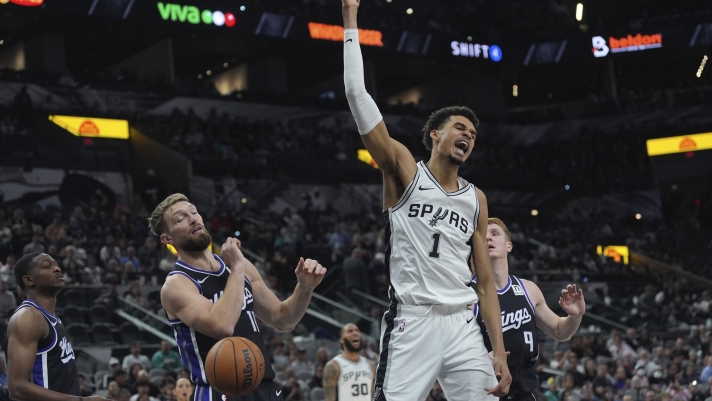 San Antonio Spurs center Victor Wembanyama (1) reacts as he scores over Sacramento Kings forward Domantas Sabonis (11) during the second half of an NBA basketball game in San Antonio, Monday, Nov. 11, 2024. (AP Photo/Eric Gay)