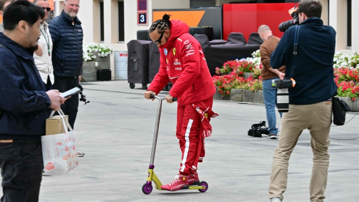 Ferrari's British driver Lewis Hamilton rides a scooter as he arrives at the track for the first day of the Formula One pre-season testing at the Bahrain International Circuit in Sakhir on February 26, 2025. (Photo by Giuseppe CACACE / AFP)