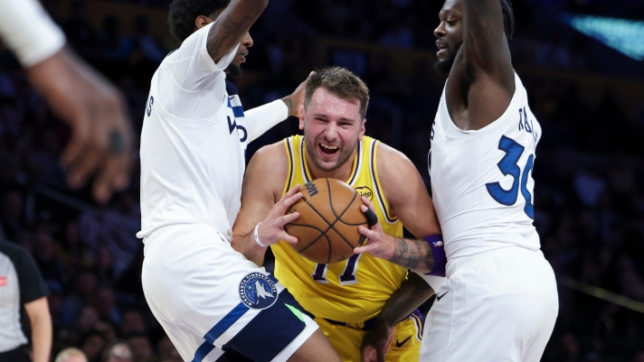 Los Angeles Lakers guard Luka Doncic, center, drives against Minnesota Timberwolves forward Jaden McDaniels, left, and forward Julius Randle during the first half of an NBA basketball game, Friday, Oct. 24, 2024, in Los Angeles. (AP Photo/Jessie Alcheh)