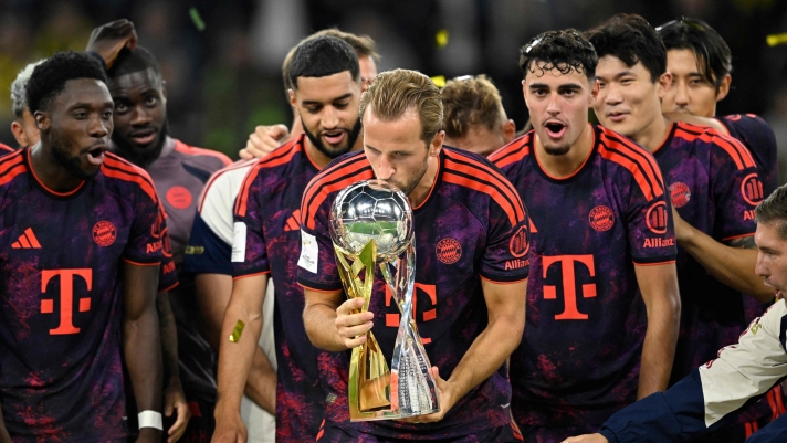 Bayern Munich's English forward #09 Harry Kane (C) kisses the trophy as he celebrates with his teammates winning the Franz Beckenbauer Supercup football match between Borussia Dortmund and FC Bayern Munich on August 22, 2026 in Dortmund, western Germany. (Photo by INA FASSBENDER / AFP) / DFL REGULATIONS PROHIBIT ANY USE OF PHOTOGRAPHS AS IMAGE SEQUENCES AND/OR QUASI-VIDEO