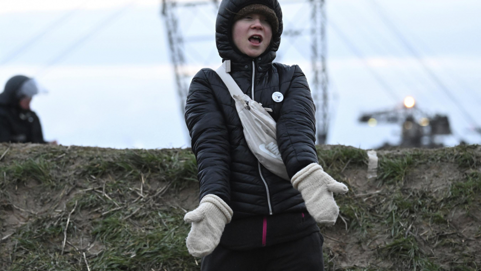 Climate activist Greta Thunberg stands between Keyenberg and Lützerath under police guard on the edge of the open pit mine and dances in Erkelenz, Germany, Sunday, Jan. 15, 2023. The energy company RWE wants to excavate the coal lying under Luetzerath, for this purpose, the hamlet on the territory of the city of Erkelenz at the opencast lignite mine Garzweiler II is to be demolished. (Federico Gambarini/dpa via AP)