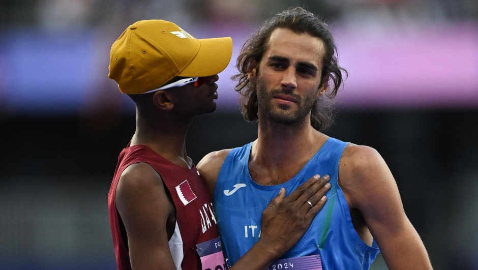 TOPSHOT - Qatar's Mutaz Essa Barshim (L) comforts Italy's Gianmarco Tamberi after he missed to clear the bar on his third attempt in the men's high jump final of the athletics event at the Paris 2024 Olympic Games at Stade de France in Saint-Denis, north of Paris, on August 10, 2024. (Photo by Ben STANSALL / AFP)