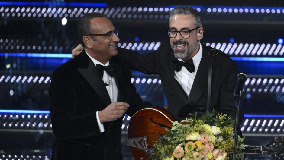 Italian singer Brunori Sas (R) and R) and Sanremo Festival host and artistic director Carlo Conti on stage at the Ariston theatre during the 75th edition of the Sanremo Italian Song Festival, in Sanremo, Italy, 15 February 2025. The music festival will run from 11 to 15 February 2025.  ANSA/ETTORE FERRARI