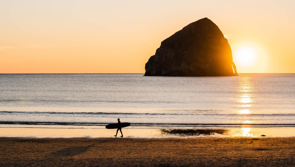 Surfer walking on the beach at sunset in Pacific City, Oregon in Pacific City, Oregon, United States