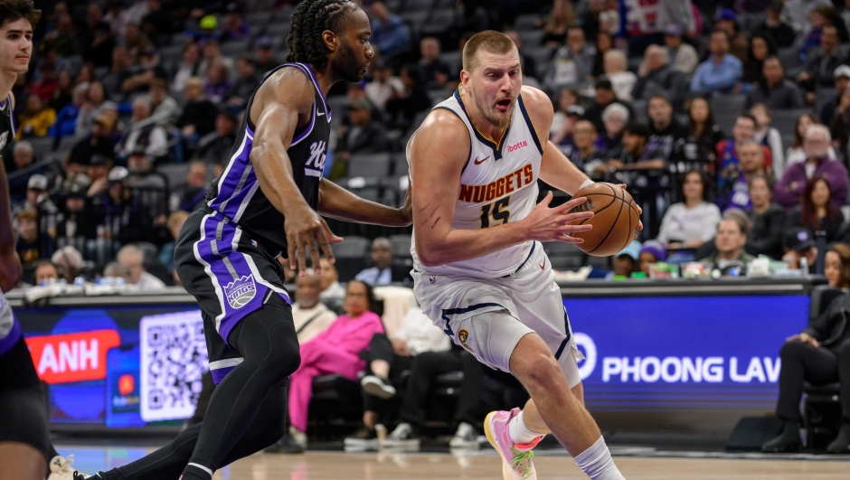 Denver Nuggets center Nikola Jokic (15) drives past Sacramento Kings forward Precious Achiuwa during the first half of an NBA basketball game in Sacramento, Calif., Thursday, Dec. 11, 2025. (AP Photo/Randall Benton)