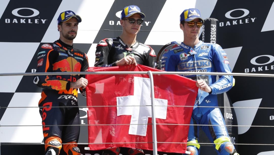 Il podio del Mugello: Fabio Quartararo, Miguel Oliveira e Joan Mir mostrano la bandiera svizzera in ricordo di Jason Dupasquier. Lapresse