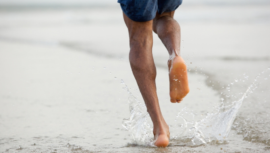 Rear view low angle view of a man running barefoot in water
