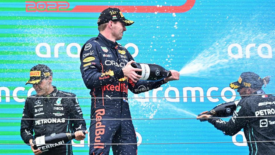 Second placed Mercedes' British driver Lewis Hamilton (R), winner Red Bull Racing's Dutch driver Max Verstappen (C) and third placed Mercedes' British driver George Russell spray with champagne as they celebrate on the podium after the Formula One Hungarian Grand Prix at the Hungaroring in Mogyorod near Budapest, Hungary, on July 31, 2022. (Photo by Attila KISBENEDEK / AFP)