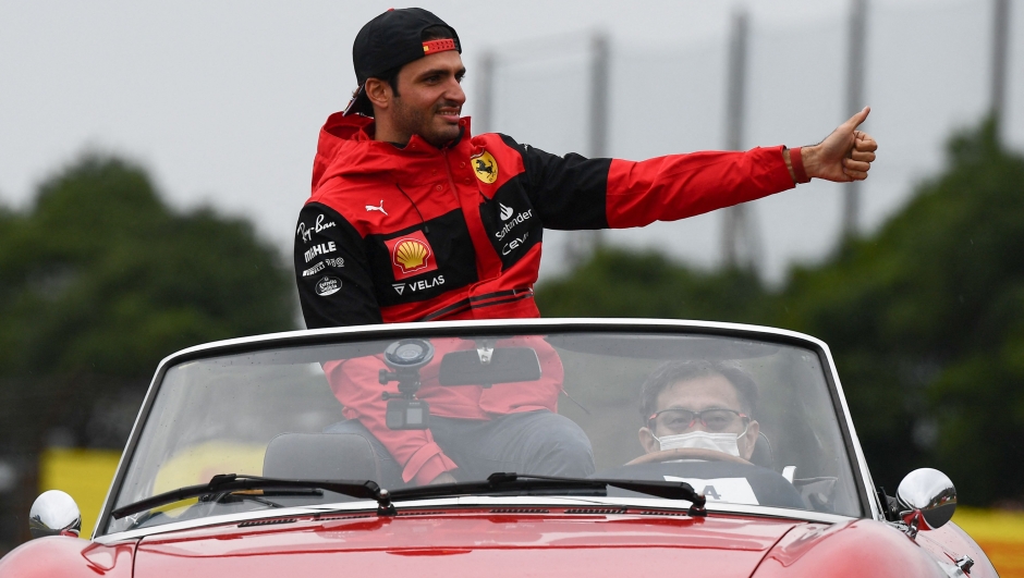 Ferrari's Spanish driver Carlos Sainz Jr (L) waves as he takes part in the drivers' parade ahead of the Formula One Japanese Grand Prix at Suzuka, Mie prefecture on October 9, 2022. (Photo by Toshifumi KITAMURA / AFP)