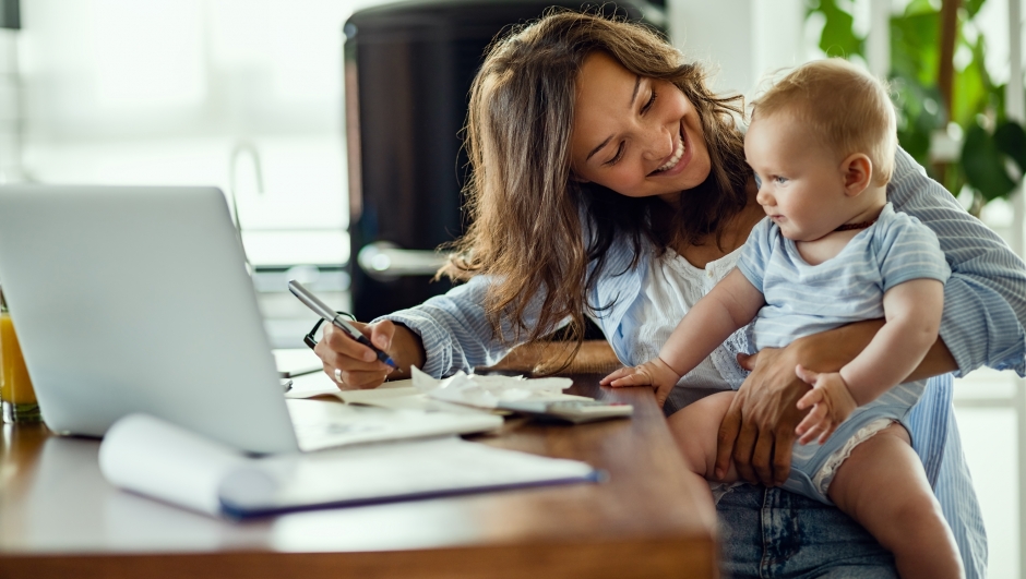 Young happy mother going through home finances and communicating with her baby son.