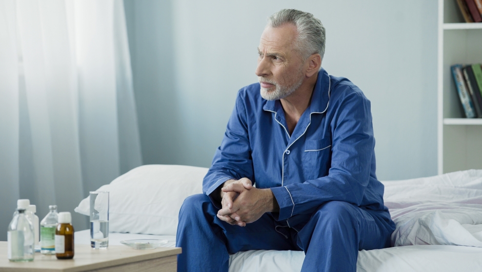 Serious aged man sitting upset and pensive on bed at home, lonely sick person, stock footage