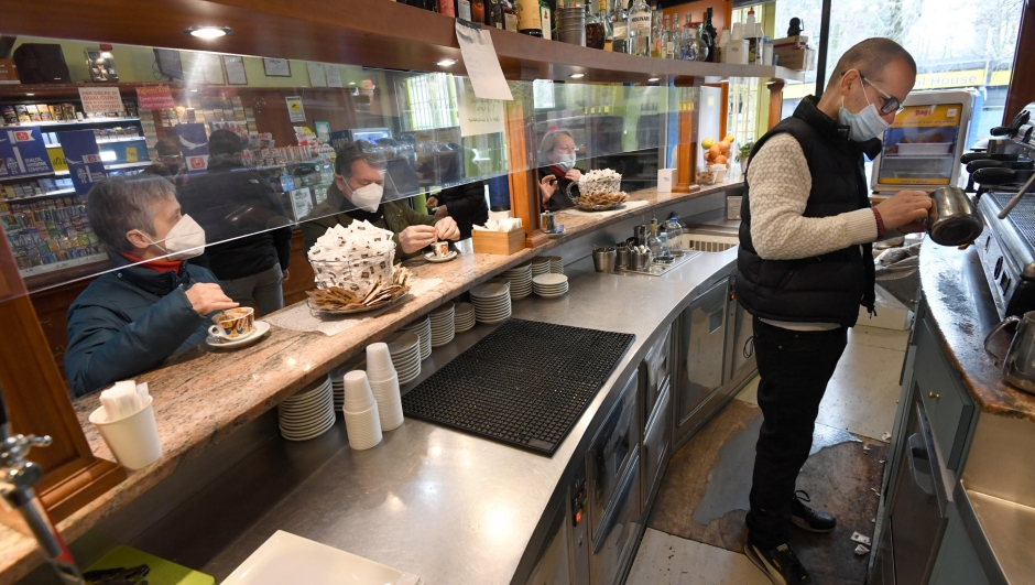 A waiter wearing a face mask prepares a coffee to customers standing at the counter of a bar in Milan, Italy, 1 February 2021. ANSA/DANIEL DAL ZENNARO