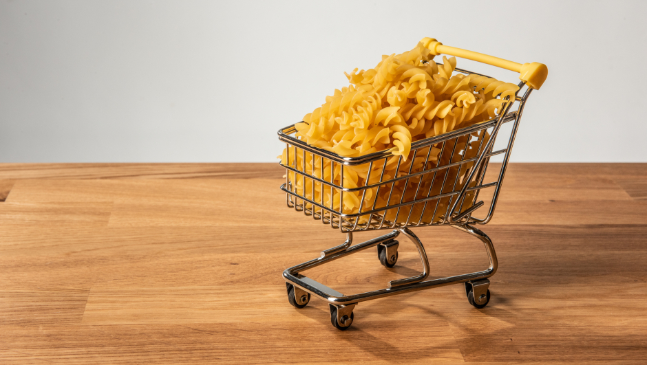 Fusilli pasta in a shopping cart on a wooden table.