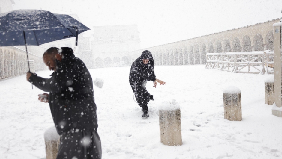 Friars play in the snow in front of the Basilica of San Francesco in Assisi, Italy, 23 January  2023. ANSA/Pietro Crocchioni